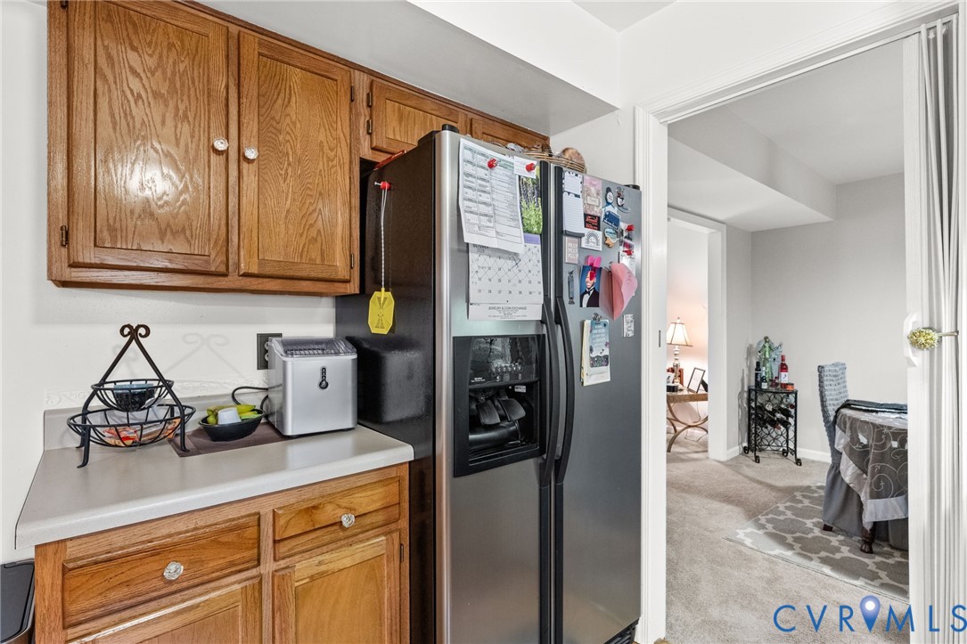 Kitchen cabinetry featuring wood-finish grain, solid surface countertop, and stainless steel refrigerator