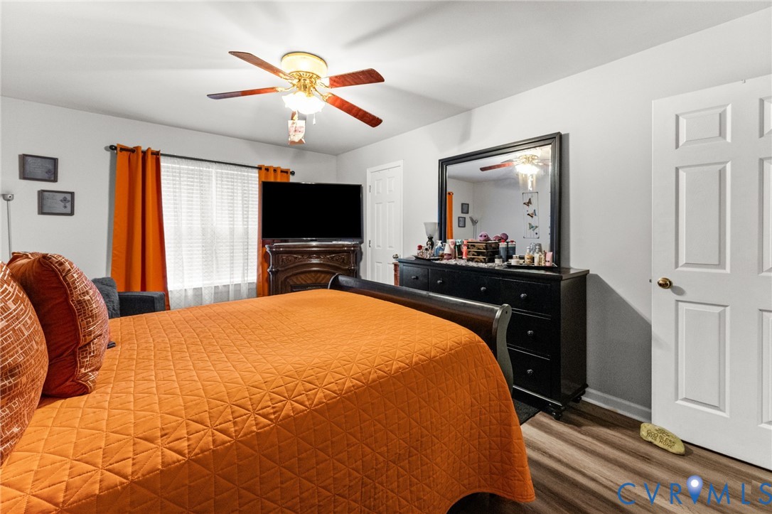 Wood-finish flooring, ceiling fan with integrated light fixture, and six-panel interior doors