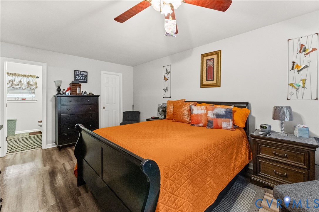 Wood-finish flooring, neutral wall paint, and ceiling-mounted light fixture with integrated fan