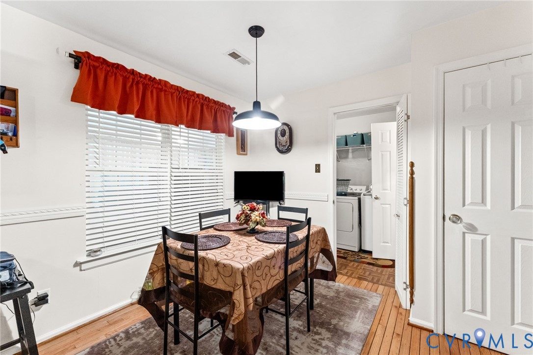 Dining space featuring wood-finish flooring, chair rail molding, and a dome pendant light fixture