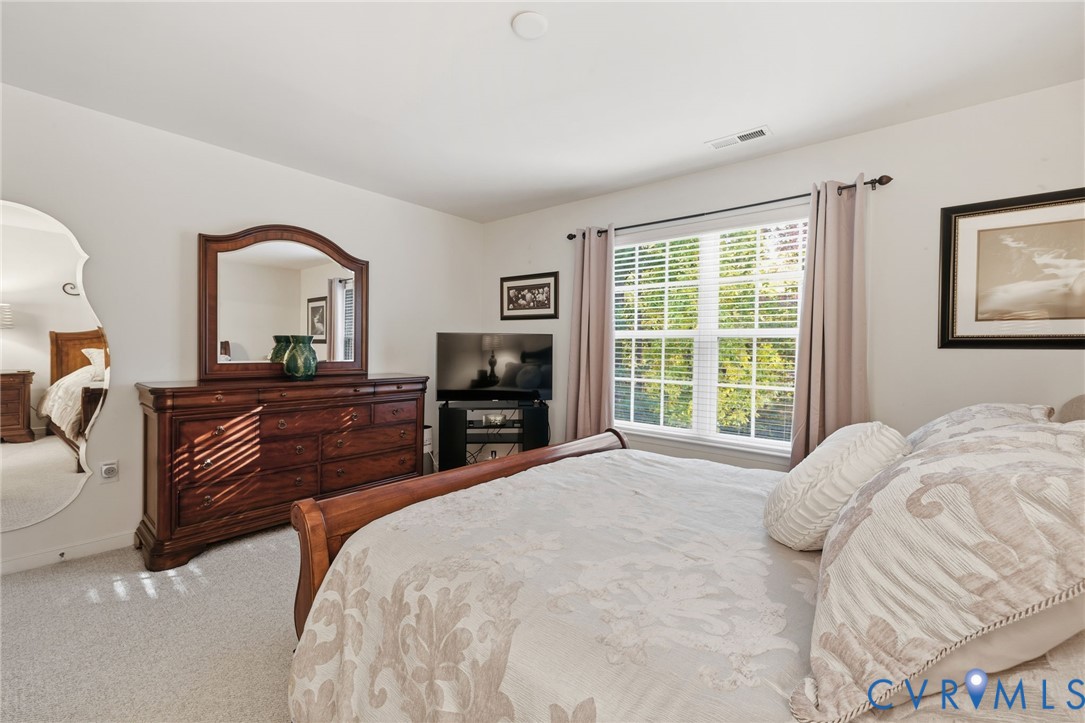 Room featuring wall-to-wall carpeting, a multi-pane window with horizontal blinds, and a full-length arched wall mirror