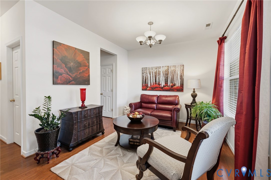 Room featuring wood-finish flooring, a multi-arm chandelier, and a horizontal window with white blinds