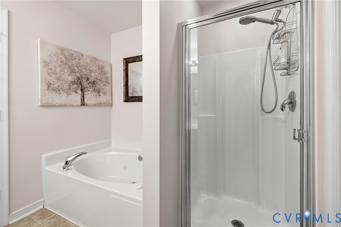 Bathroom featuring a soaking tub and a separate glass-enclosed shower stall with a handheld showerhead