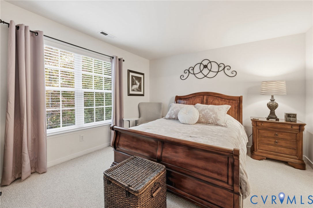 Neutral interior space featuring carpeting and a large window with horizontal blinds