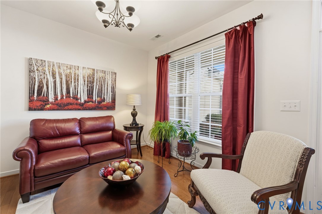 Wood-finish flooring, multi-pane window with horizontal blinds, and decorative chandelier fixture