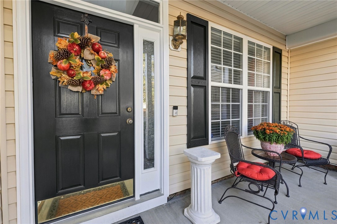 Covered entryway featuring horizontal lap siding, a paneled front door with a transom window and sidelight, and decorative window shutters Covered entryway featuring horizontal lap siding, a paneled front door with a transom window and sidelight, and decorative window shutters