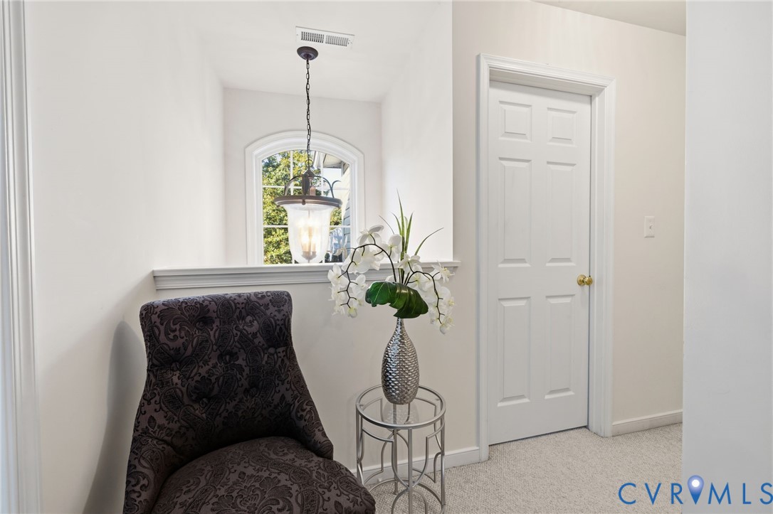 Arched window with decorative casing, six-panel interior door, and hanging pendant light fixture