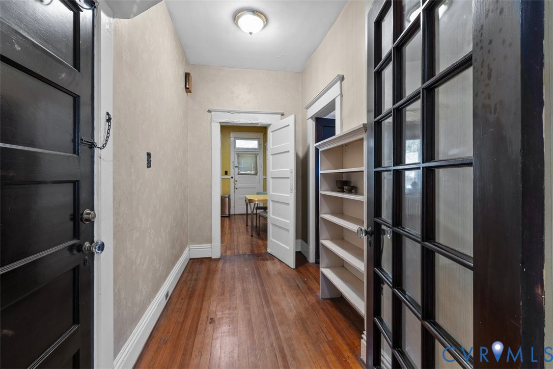 Entryway featuring wood-finish flooring, dark-finish paneled doors, multi-pane glass French doors, and built-in shelving