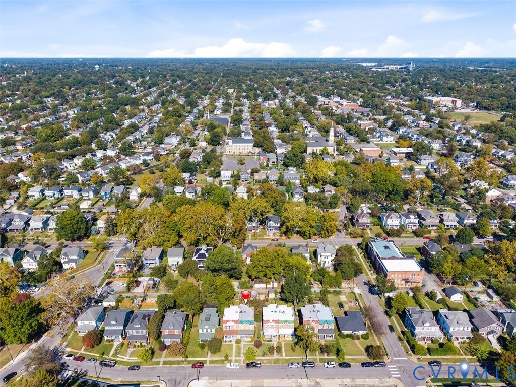 Aerial perspective of a detached residential property featuring a rectangular lot, mature trees, and street-front access