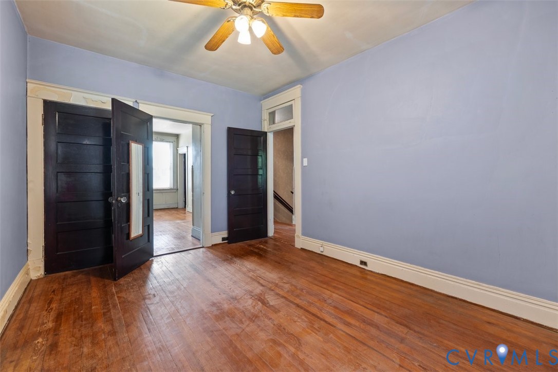 2nd bedroom with wood-finish flooring, dark-stained five-panel doors, tall white casing trim, and a ceiling-mounted light fixture