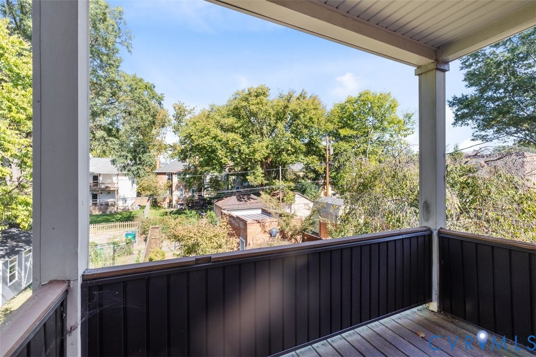 third bedroom covered outdoor balcony featuring wood-finish decking and vertical slat railing.