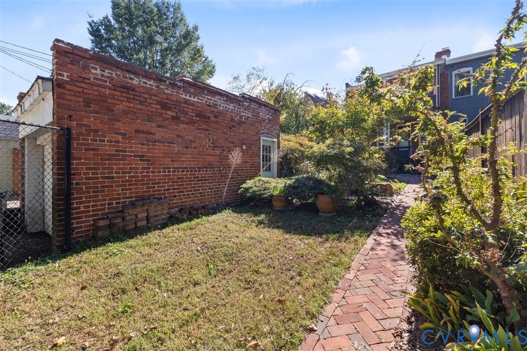 Exterior grounds featuring a brick-paved pathway, a brick-facade structure, and mature landscaping