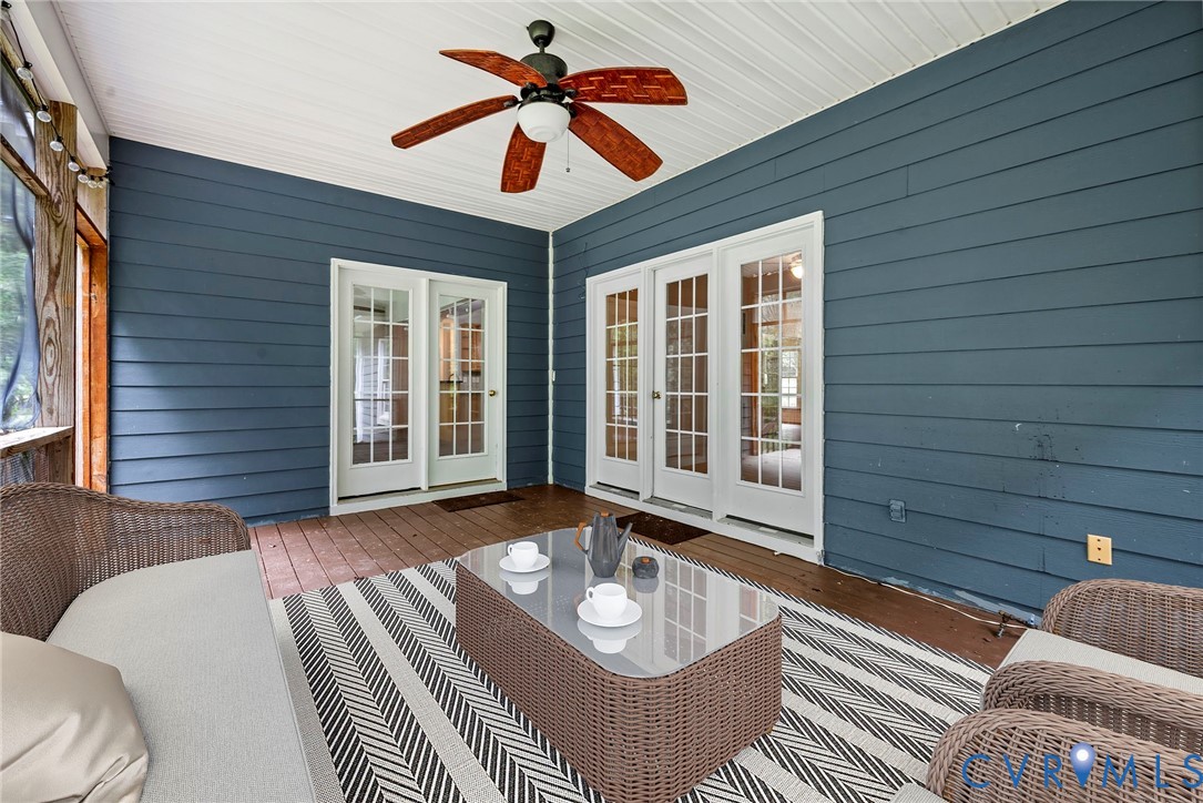 Screened porch featuring wood-finish decking, white beadboard ceiling, and a ceiling fan with integrated lighting. Virtually staged concept