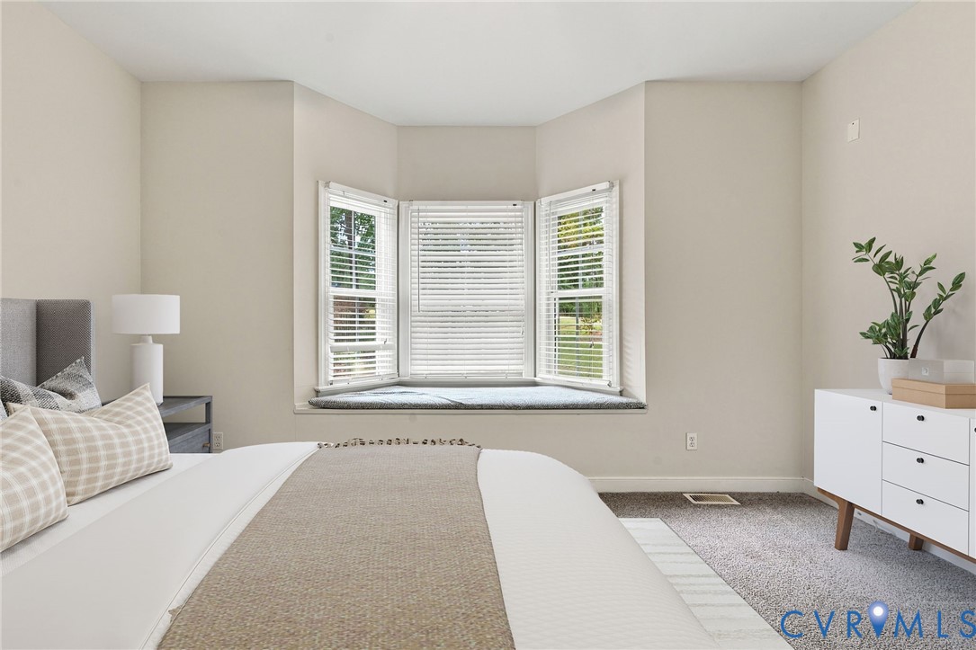 Bay window featuring a built-in bench seat and neutral carpeting. Virtually staged concept