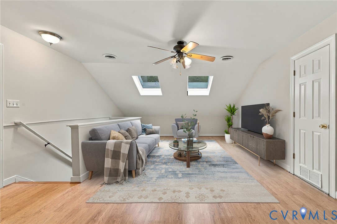 Vaulted ceilings featuring dual skylights, vinyl flooring, and a ceiling fan with integrated lighting. Virtually staged concept