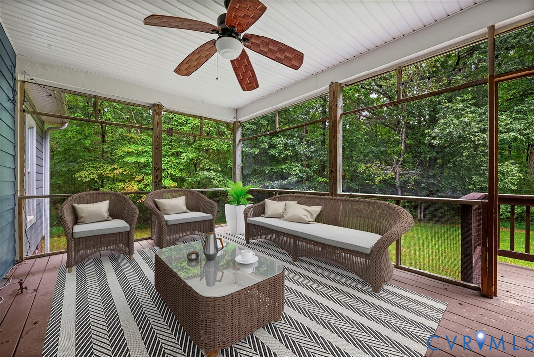 Screened porch featuring wood-finish decking, white beadboard ceiling, and a ceiling fan with integrated lighting. Virtually staged concept