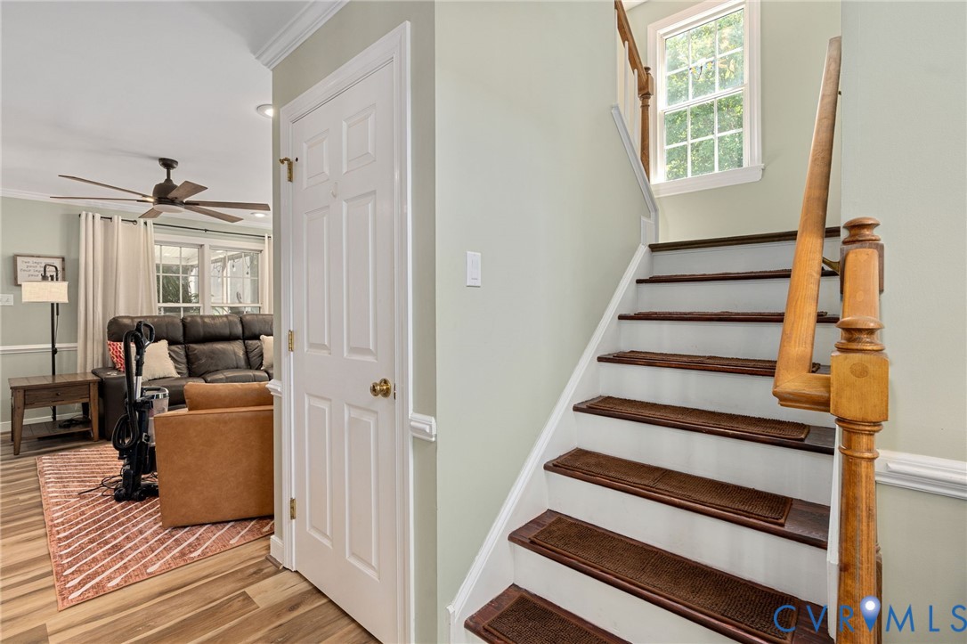 Staircase featuring white risers, wood-finish treads, and a traditional wood banister, complemented by a multi-pane window and crown molding