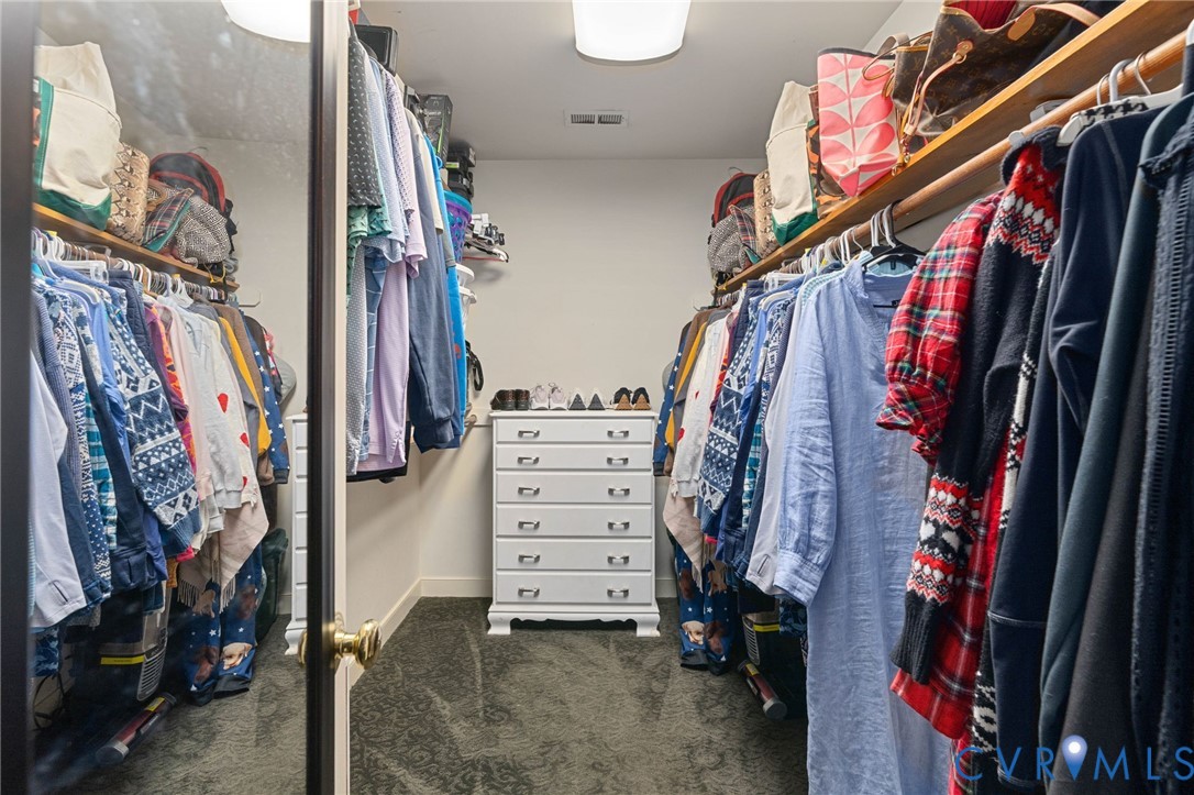 Walk-in closet featuring dual-sided wall-mounted shelving and a full-length mirrored door