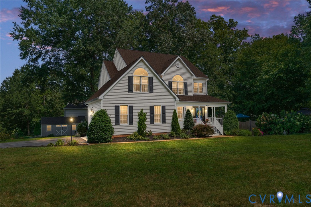 Two-story residence featuring horizontal siding, arched windows, a covered front porch, and a detached outbuilding