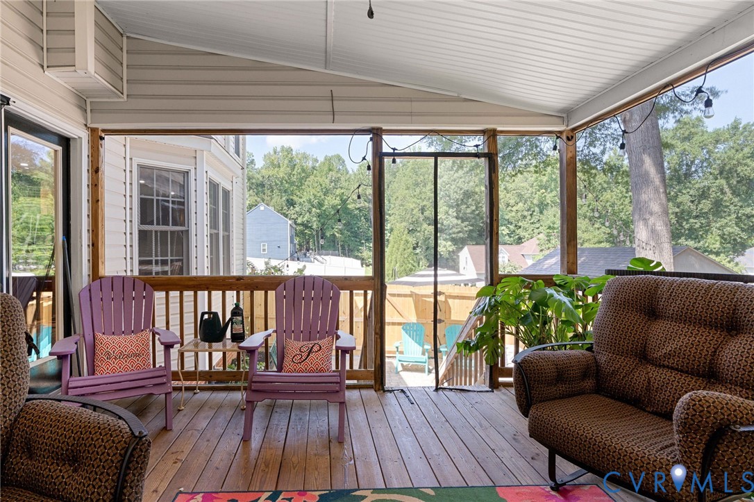 Screened porch featuring a wood-plank floor, vaulted ceiling, and wooden railing