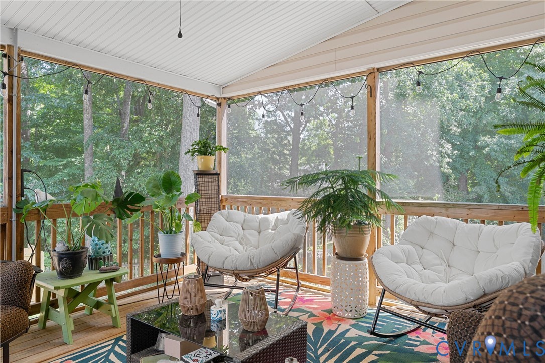 Screened-in porch featuring wood-plank flooring, wood railing, and a vaulted ceiling