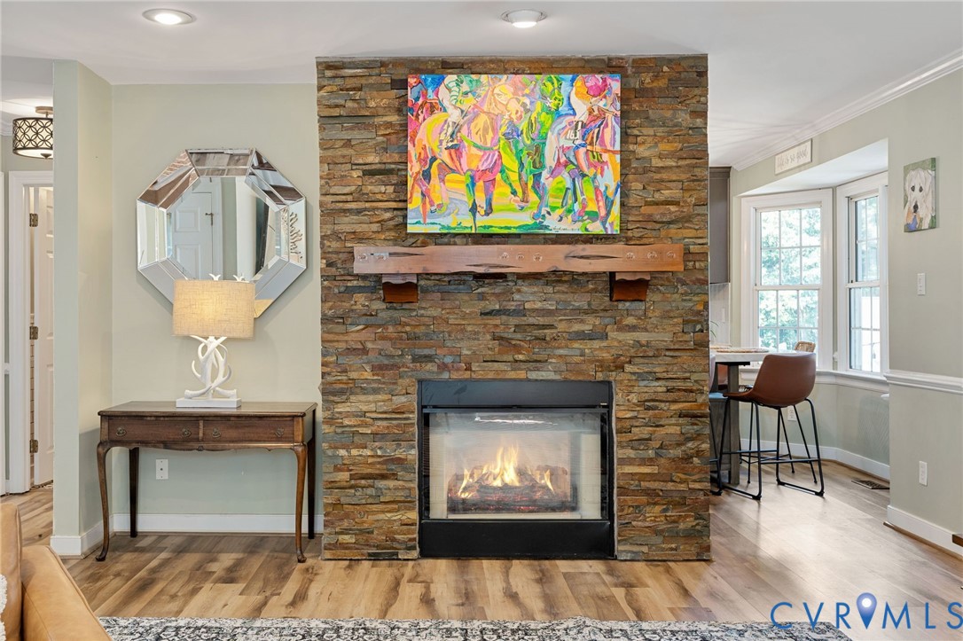 Floor-to-ceiling stone fireplace with a prominent timber mantel, recessed ceiling lighting, and wood-finish flooring