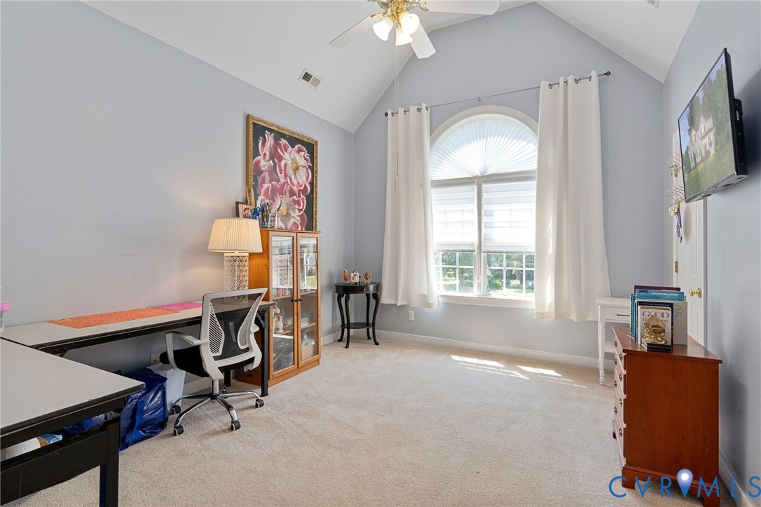 Vaulted ceiling, arched window, wall-to-wall carpeting, and a ceiling fan with integrated lighting