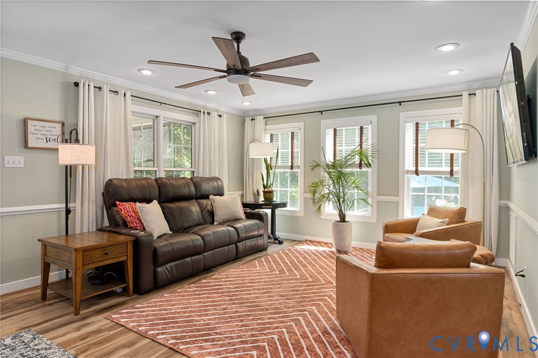 Living area featuring wood-finish flooring, a ceiling fan with integrated lighting, recessed lighting, and crown molding