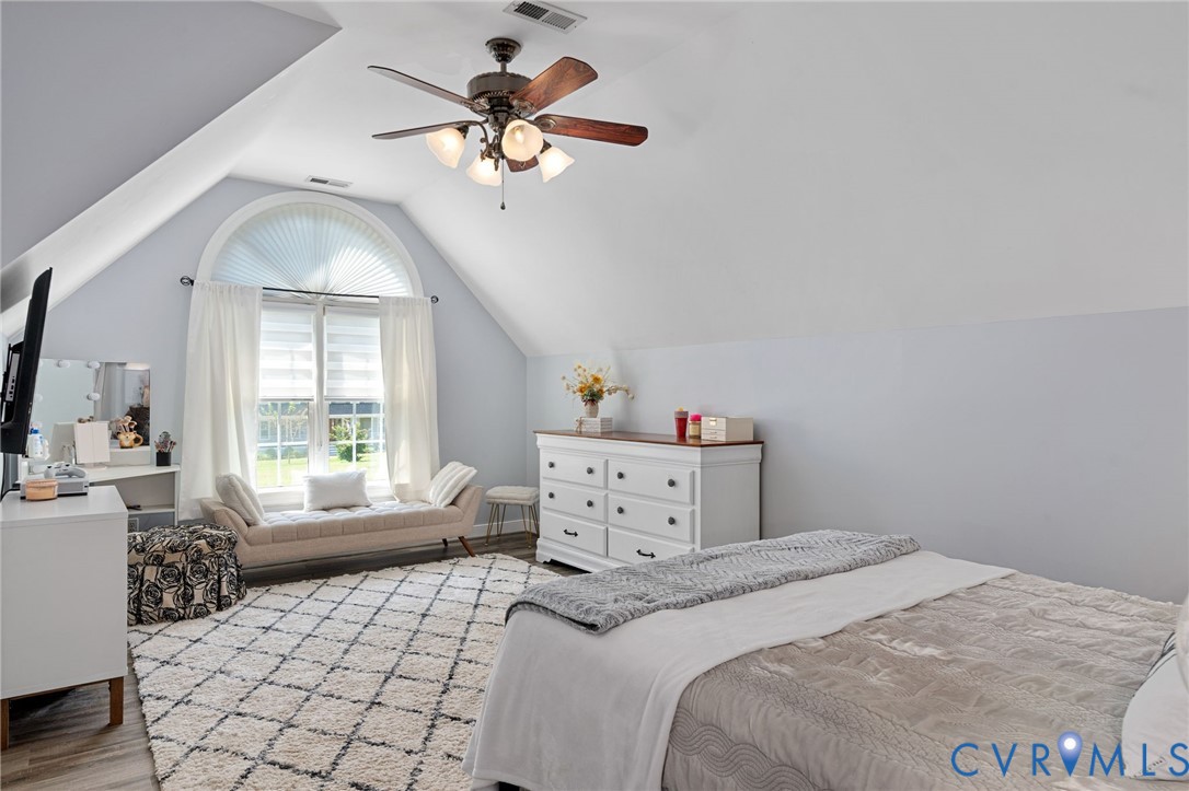 Vaulted ceilings, arched window with multi-pane glass, and multi-blade ceiling fan with integrated lighting