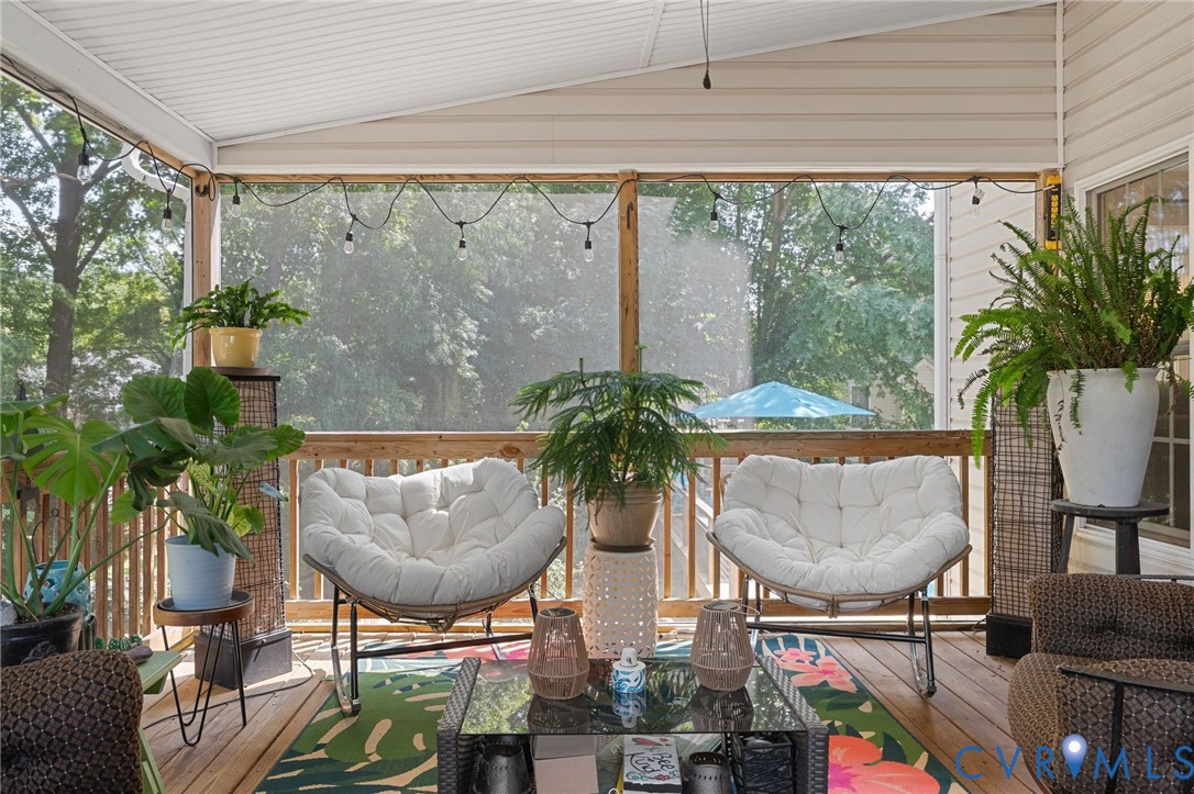 Screened-in porch featuring a wood-plank deck, overhead ceiling panels, and a wood-slat railing