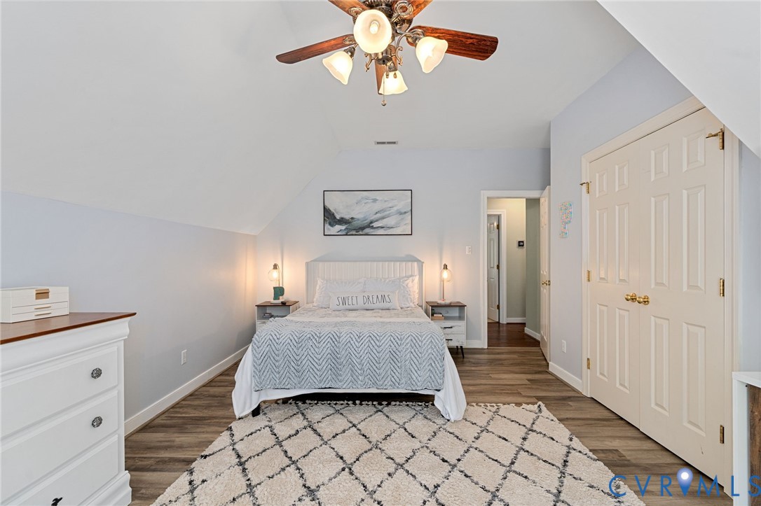 Vaulted ceilings, wood-finish flooring, and a multi-bulb ceiling fan with integrated lighting