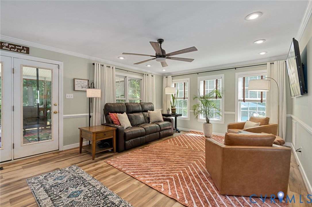 Living area featuring wood-finish flooring, recessed lighting, a ceiling fan, crown molding, and a full-glass entry door