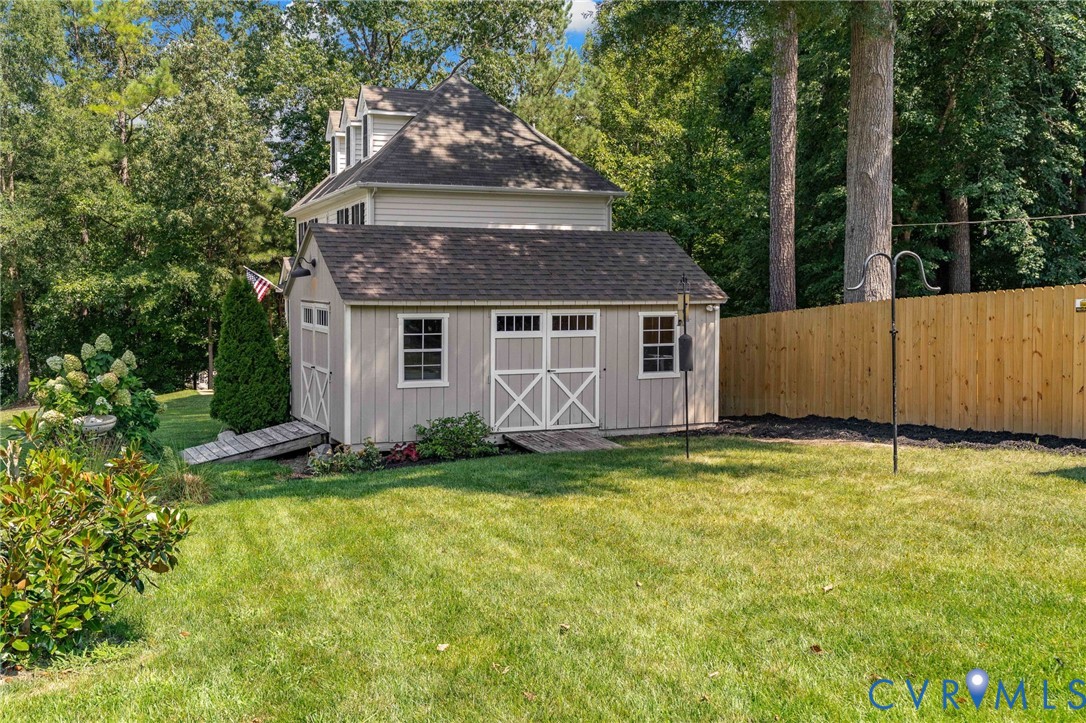 Backyard featuring a detached storage shed, privacy fencing, manicured lawn, and mature trees