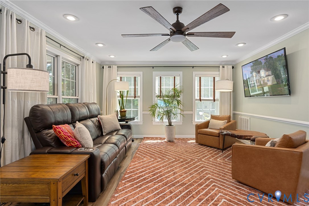 Living room featuring crown molding, chair rail trim, recessed lighting, multi-blade ceiling fan, and triple windows