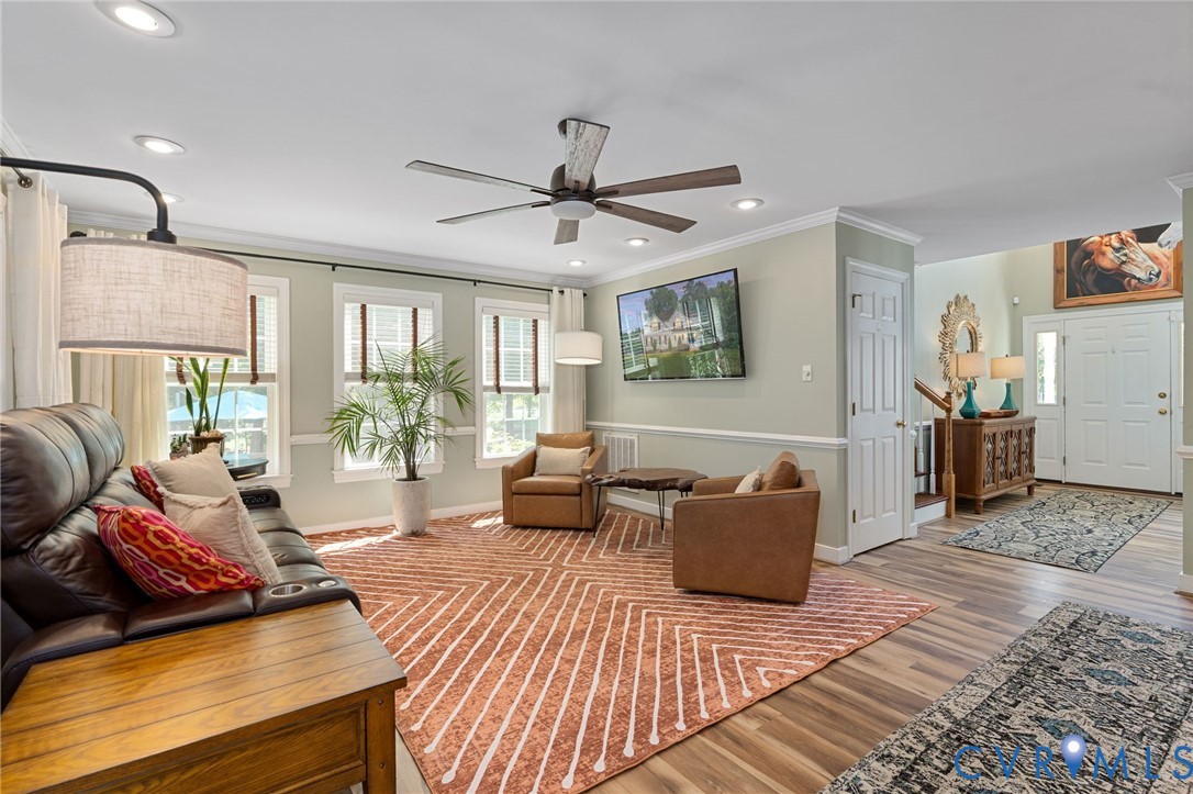 Living area featuring wood-finish flooring, recessed lighting, crown molding, chair rail trim, and a ceiling fan