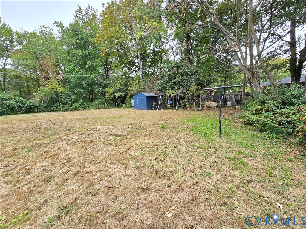 Expansive backyard featuring mature trees, a metal storage shed, and a permanent clothesline pole