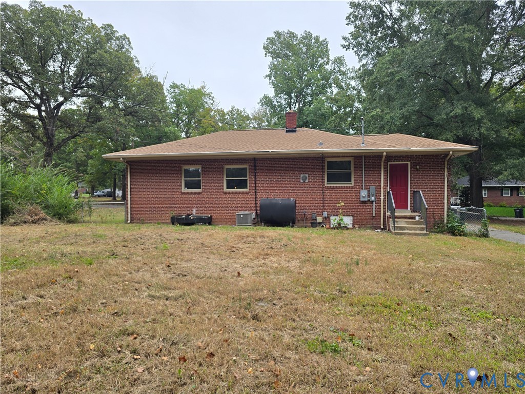 Red brick exterior featuring a hip roof, chimney, and mature perimeter trees