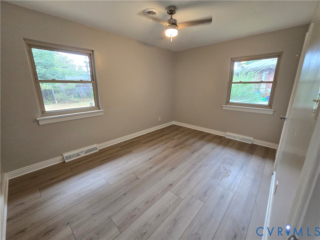 Bedroom 2 with LVP flooring, two double-hung windows, and a ceiling fan with integrated lighting