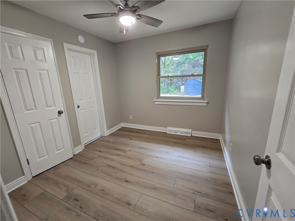 Bedroom 3 with LVP flooring, a multi-panel door, and a ceiling fan with integrated lighting