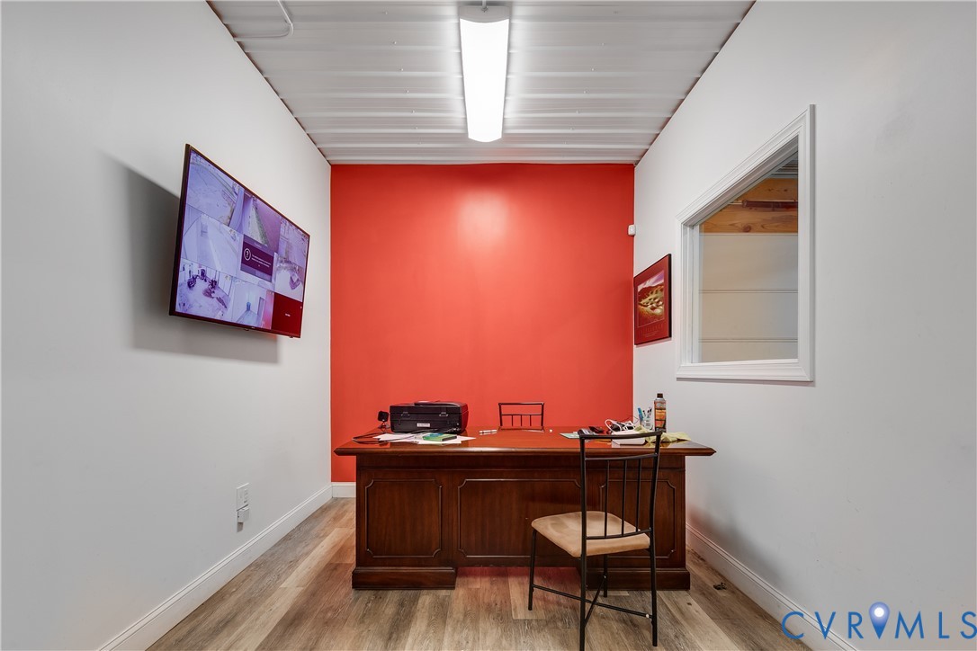 Interior space featuring a corrugated metal ceiling, wood-finish flooring, a wall-mounted rectangular window, and a linear fluorescent lighting fixture Interior space featuring a corrugated metal ceiling, wood-finish flooring, a wall-mounted rectangular window, and a linear fluorescent lighting fixture