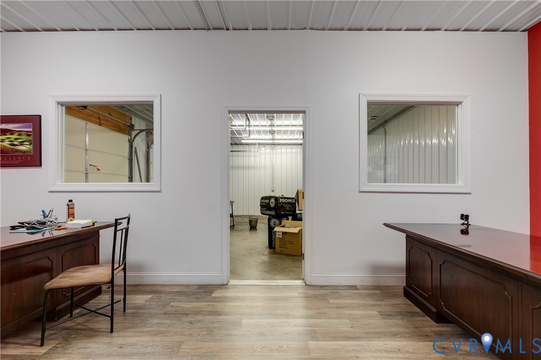 Interior space featuring wood-finish flooring, white walls, two windows with white trim, and a central open doorway Interior space featuring wood-finish flooring, white walls, two windows with white trim, and a central open doorway
