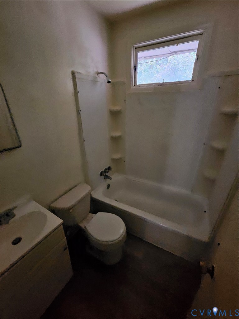 Bathroom featuring a tub-shower combination with integrated shelving, a wall-mounted showerhead, a porcelain vanity sink, and a high-set window Bathroom featuring a tub-shower combination with integrated shelving, a wall-mounted showerhead, a porcelain vanity sink, and a high-set window