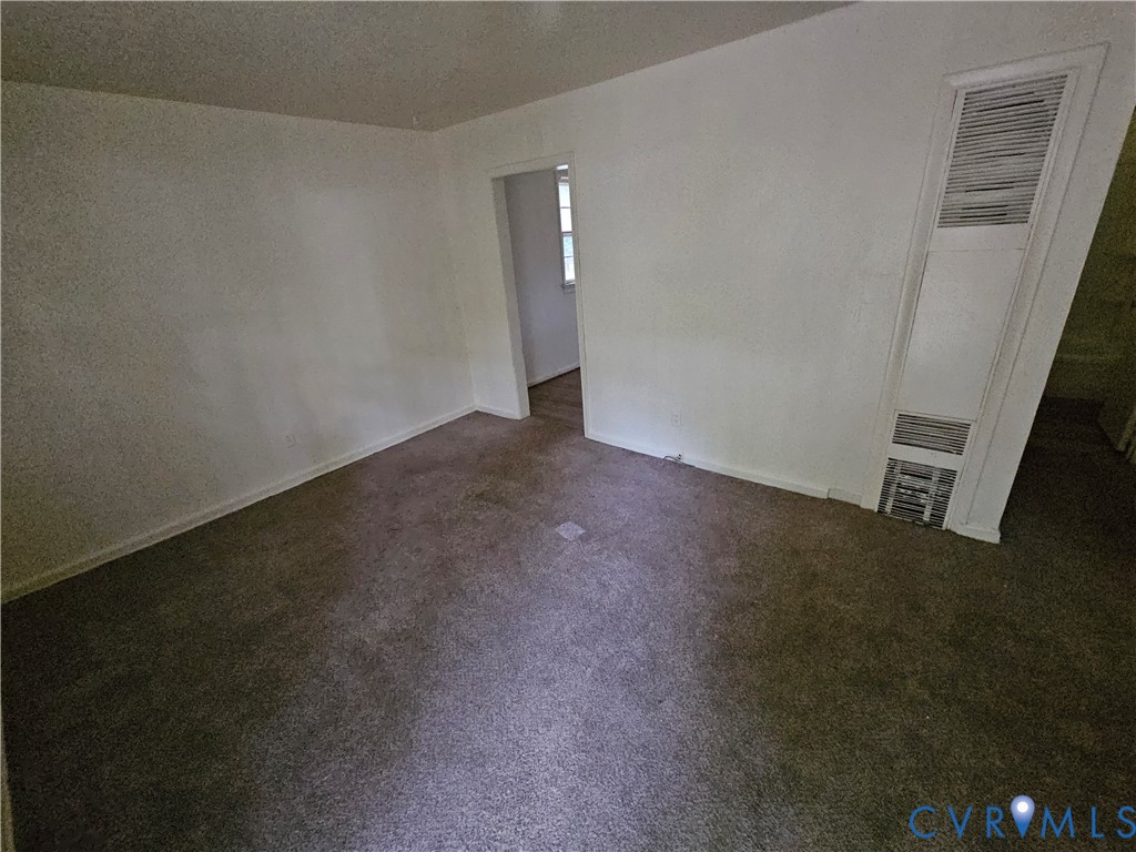 Neutral-toned carpeting, wall-mounted heating unit, and interior doorway Neutral-toned carpeting, wall-mounted heating unit, and interior doorway