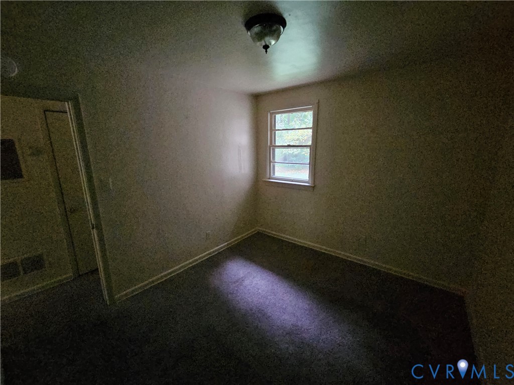 Interior space featuring neutral wall tones, carpeted flooring, a multi-pane window, and a ceiling-mounted light fixture Interior space featuring neutral wall tones, carpeted flooring, a multi-pane window, and a ceiling-mounted light fixture
