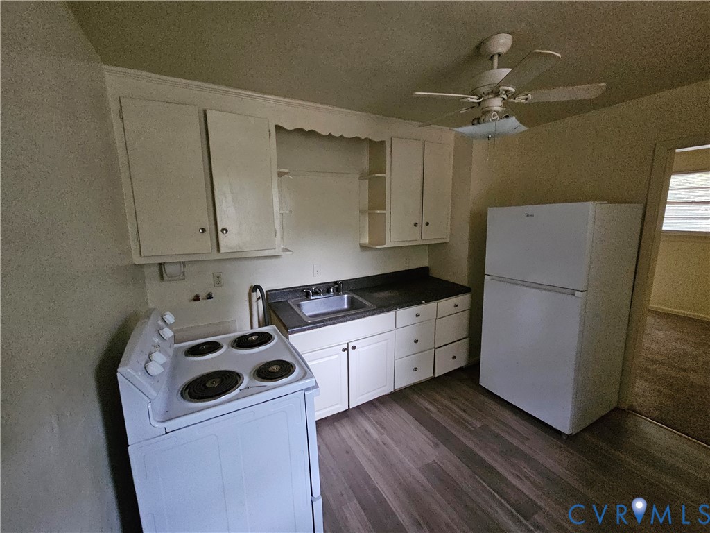Kitchen featuring white cabinetry, wood-finish flooring, a stainless steel sink, a top-mount electric range, and a ceiling-mounted fan Kitchen featuring white cabinetry, wood-finish flooring, a stainless steel sink, a top-mount electric range, and a ceiling-mounted fan