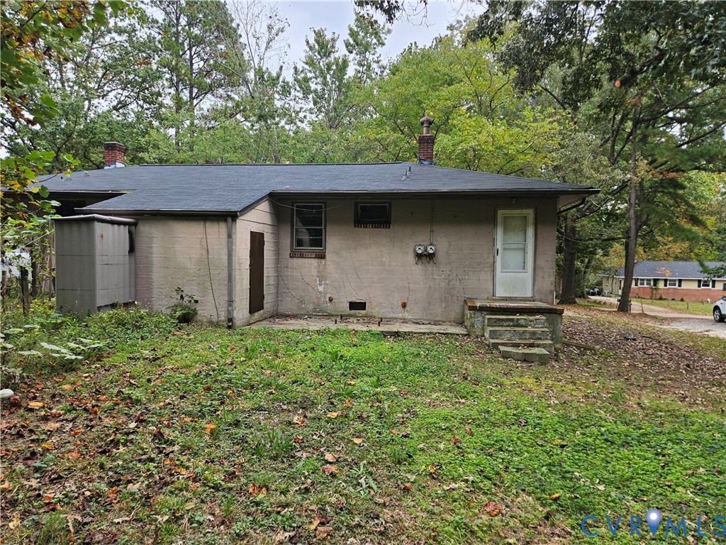 Single-story residence featuring a masonry exterior, asphalt shingle roof, two brick chimneys, and a concrete stoop Single-story residence featuring a masonry exterior, asphalt shingle roof, two brick chimneys, and a concrete stoop