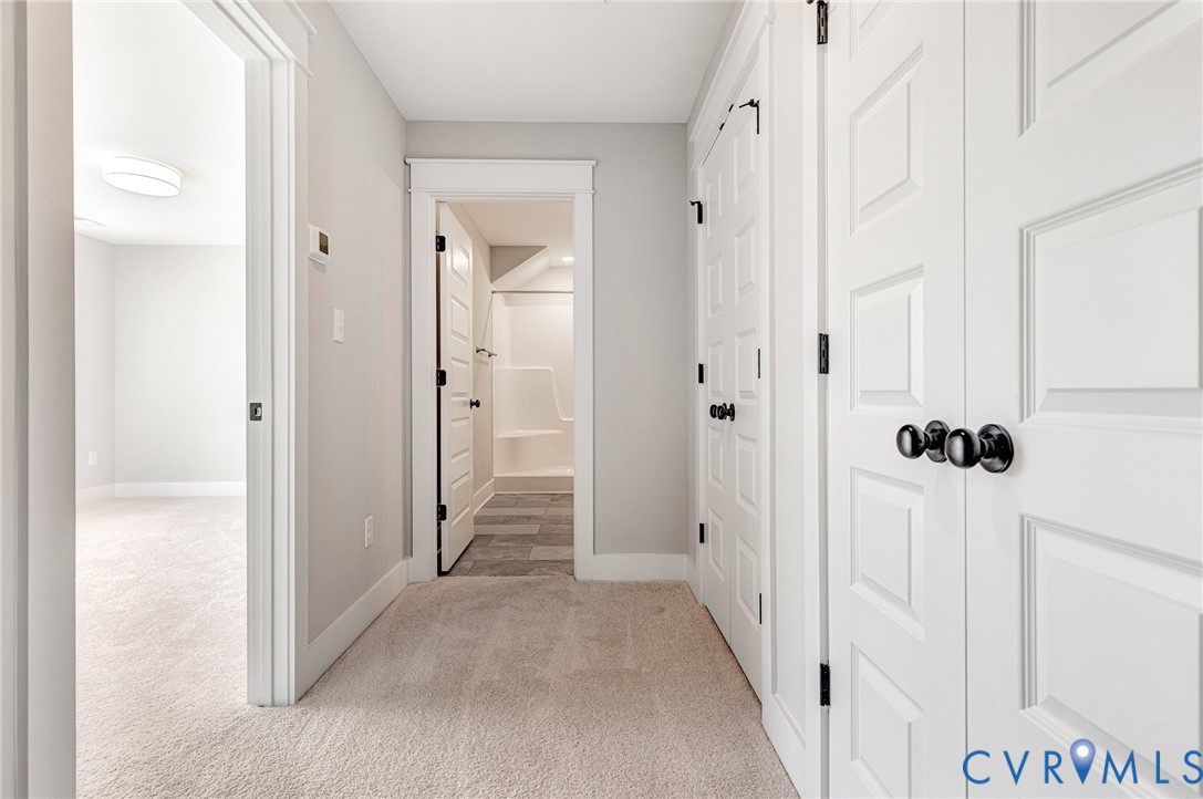 The property features light-colored carpeting throughout the hallway and into an adjacent room