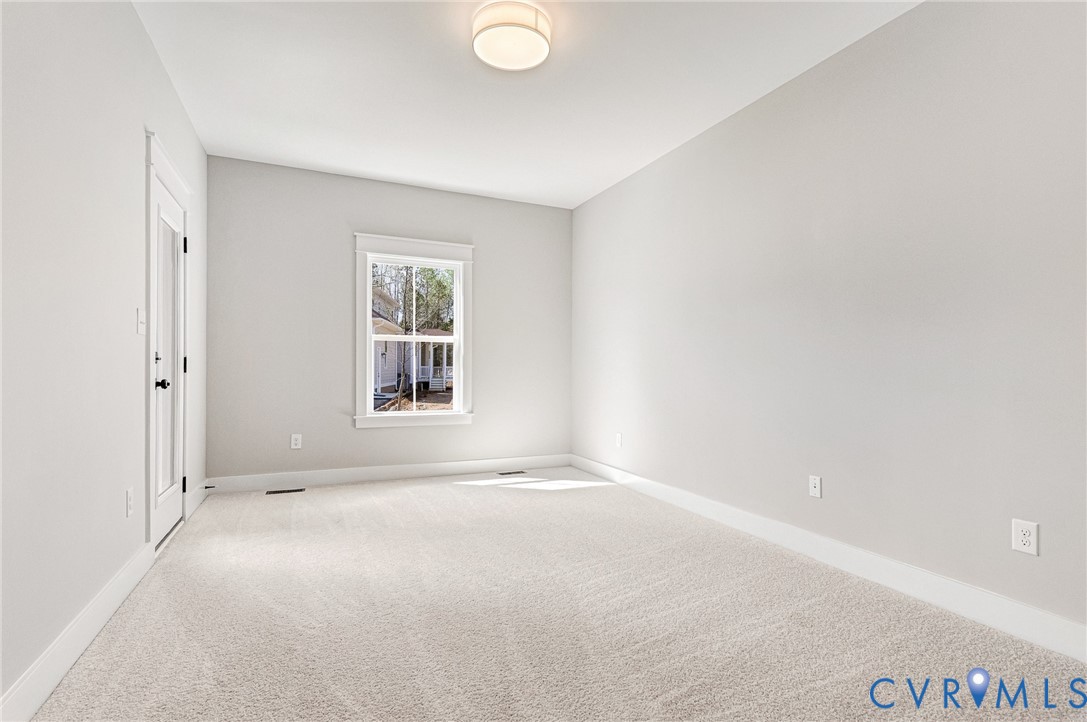 This room features light-colored walls and carpeting, a window with trim, and a door with a glass panel
