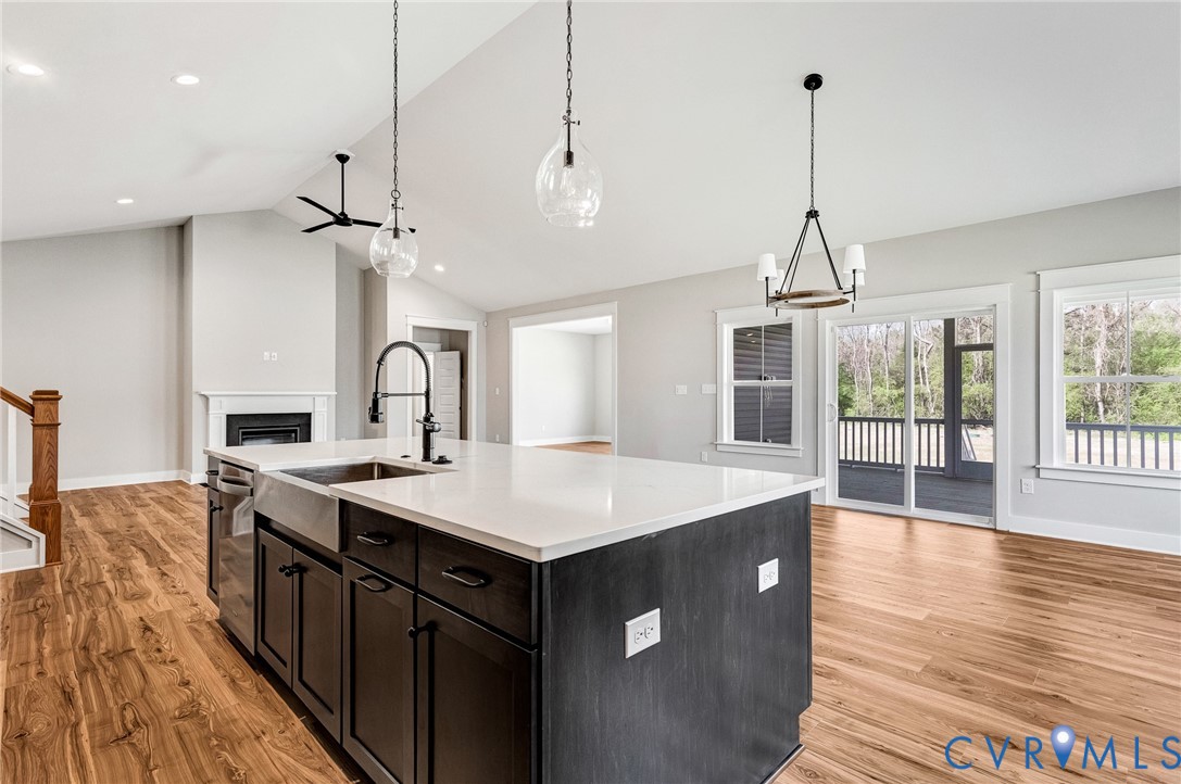 The property features an open-concept living area with vaulted ceilings, hardwood style flooring, a contemporary kitchen island with a farmhouse sink, and a fireplace