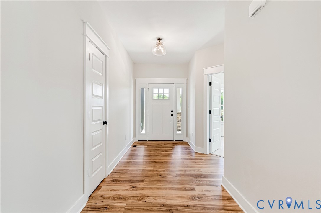 Inviting entry hall featuring hardwood floors, white trim, and a white front door with glass panels